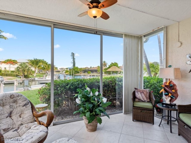 sunroom with ceiling fan and a water view