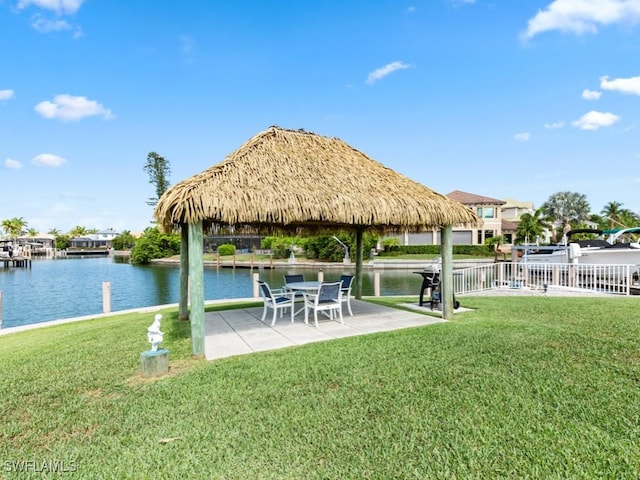 view of dock featuring a lawn, a patio area, and a water view