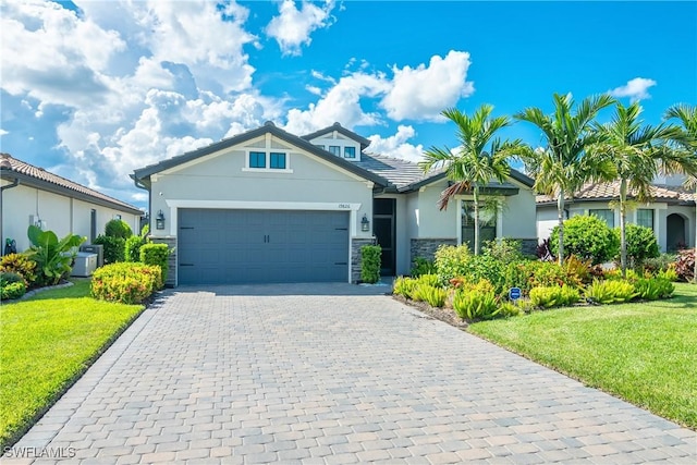 view of front of property with central AC, a front yard, and a garage