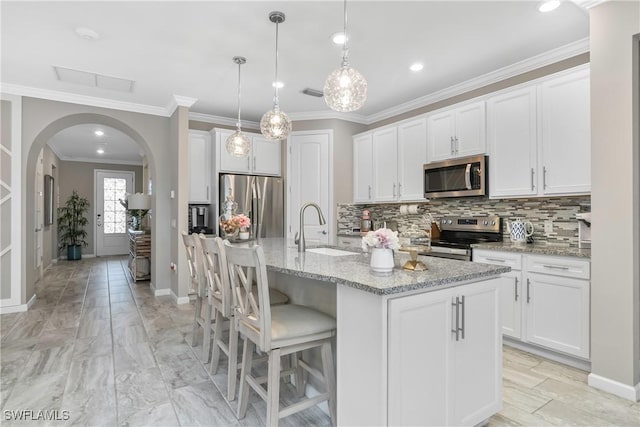 kitchen featuring sink, white cabinets, stainless steel appliances, and a center island with sink