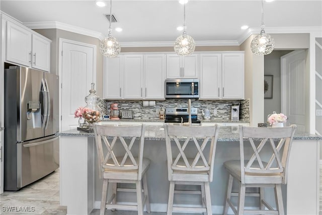 kitchen featuring white cabinets, hanging light fixtures, and appliances with stainless steel finishes