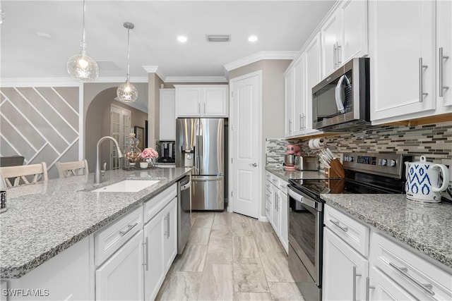 kitchen featuring appliances with stainless steel finishes, ornamental molding, a kitchen island with sink, sink, and white cabinetry