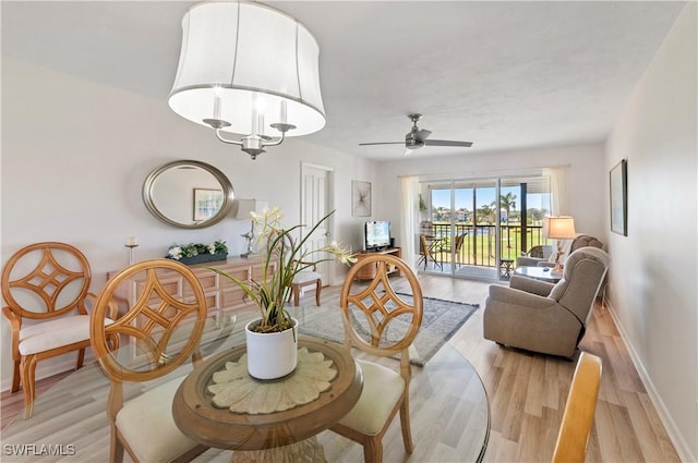 living room featuring ceiling fan with notable chandelier and light wood-type flooring