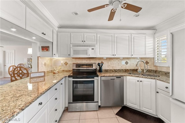 kitchen with white cabinets, sink, light tile patterned flooring, light stone counters, and stainless steel appliances