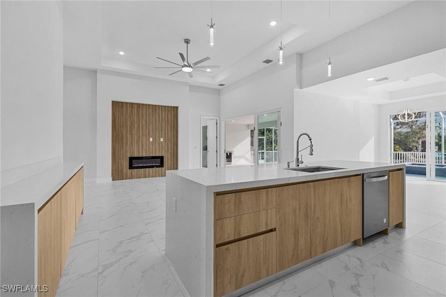 kitchen featuring ceiling fan, a spacious island, sink, and a tray ceiling