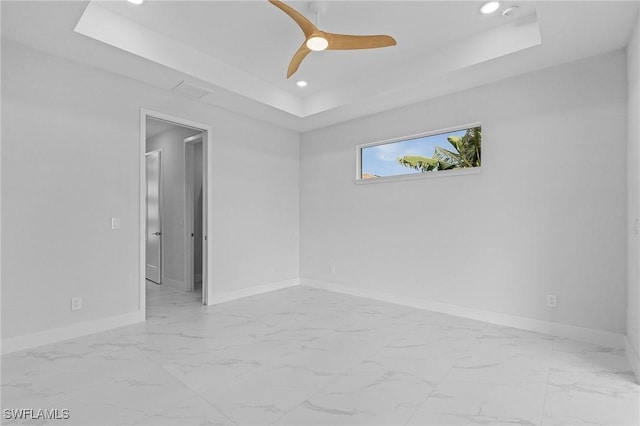 spare room featuring a tray ceiling and ceiling fan