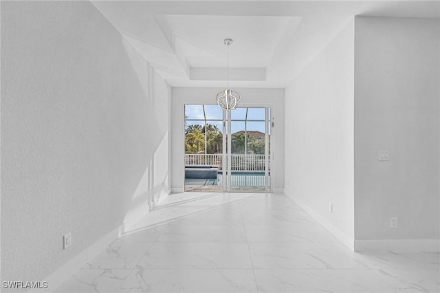 unfurnished dining area with a chandelier and a tray ceiling