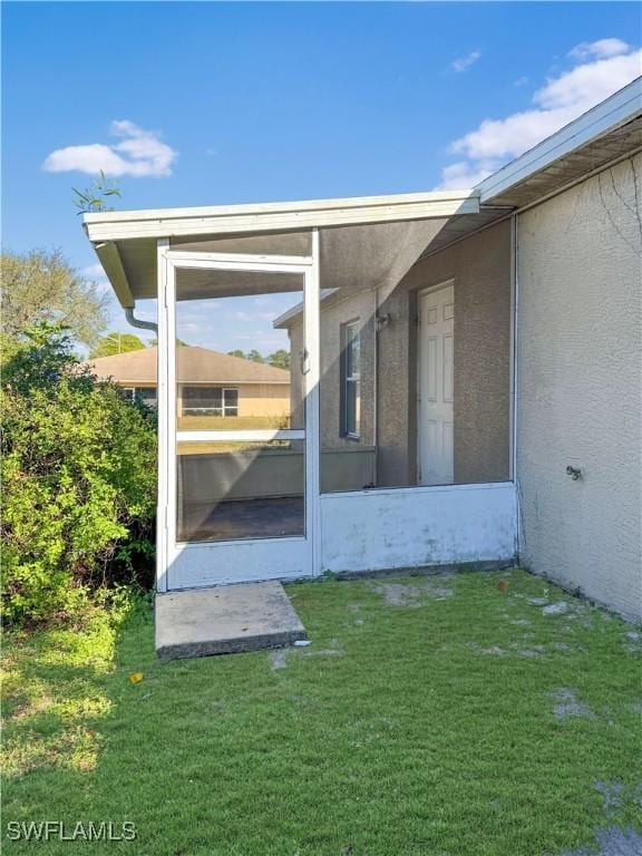 view of side of home with a sunroom and a yard