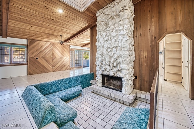 living room with a skylight, wooden walls, a fireplace, light tile patterned floors, and wood ceiling