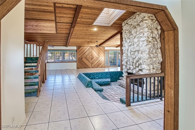 interior space with light tile patterned floors, wooden ceiling, and vaulted ceiling with skylight