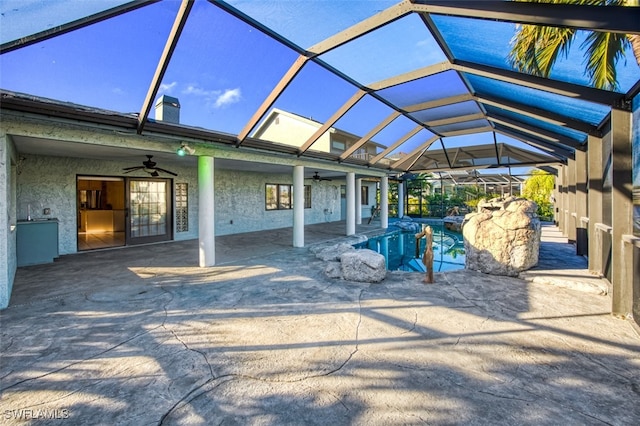 view of patio / terrace featuring ceiling fan and glass enclosure