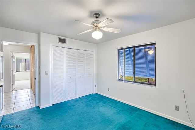 unfurnished bedroom with dark colored carpet, ceiling fan, and a closet