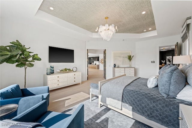 bedroom featuring a notable chandelier, light hardwood / wood-style floors, and a raised ceiling