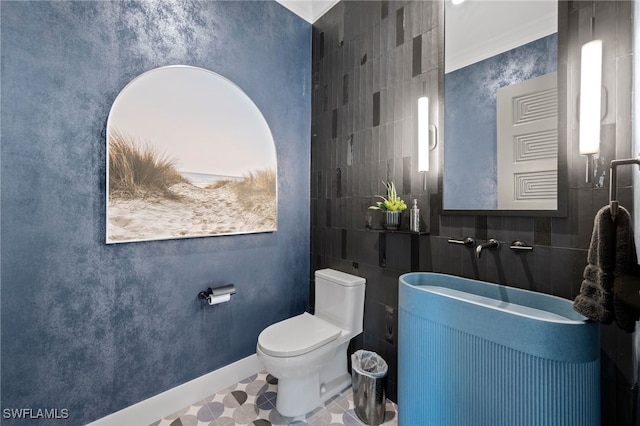 bathroom featuring tile patterned flooring, tile walls, and toilet