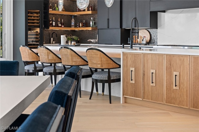 bar with backsplash, sink, and light hardwood / wood-style floors