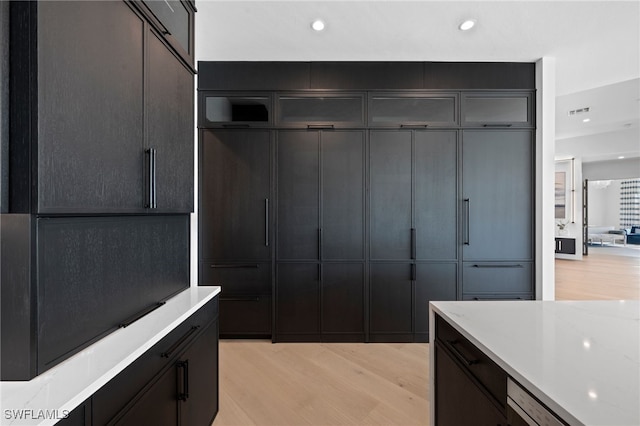 kitchen with dishwasher, light stone countertops, and light hardwood / wood-style flooring