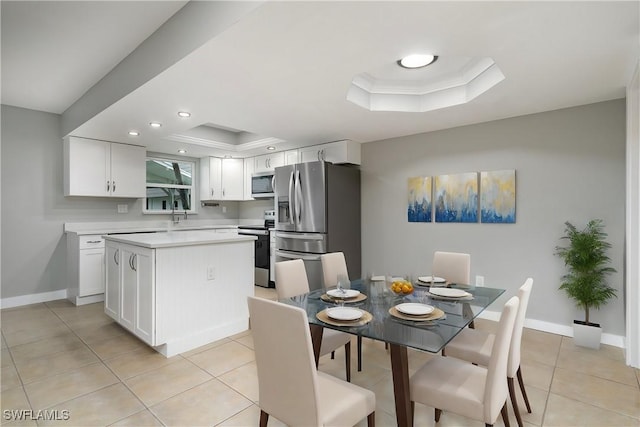 dining area with a raised ceiling, light tile patterned floors, and crown molding