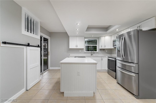 kitchen featuring appliances with stainless steel finishes, sink, a barn door, a center island, and white cabinetry