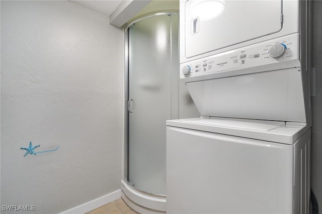 laundry area featuring stacked washer / dryer and light tile patterned flooring