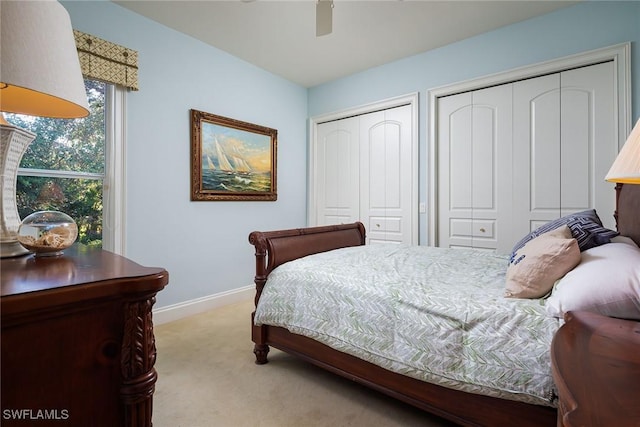 carpeted bedroom with ceiling fan and two closets