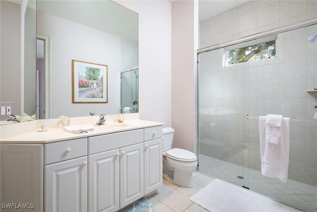 bathroom featuring tile patterned flooring, vanity, a shower with shower door, and toilet