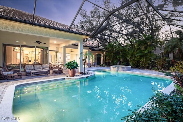 pool at dusk featuring an in ground hot tub, an outdoor hangout area, a lanai, ceiling fan, and a patio