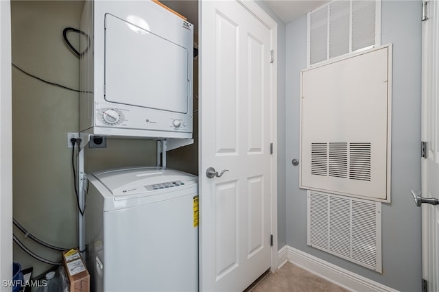 laundry area featuring light tile patterned flooring and stacked washer and clothes dryer