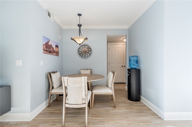 dining area featuring light wood-type flooring and ornamental molding