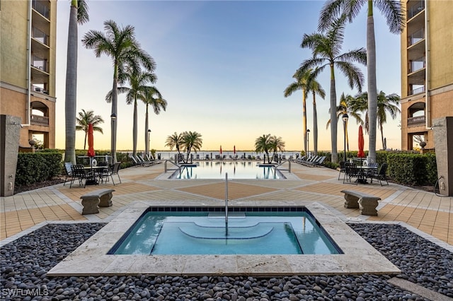 pool at dusk featuring a patio