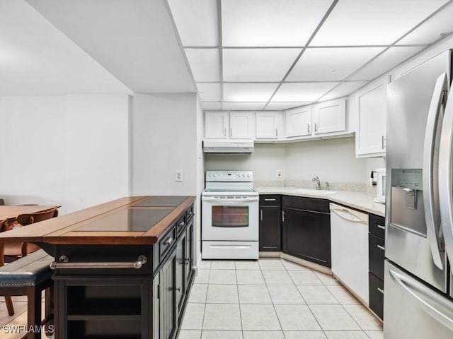 kitchen featuring a paneled ceiling, white appliances, white cabinets, sink, and light tile patterned floors