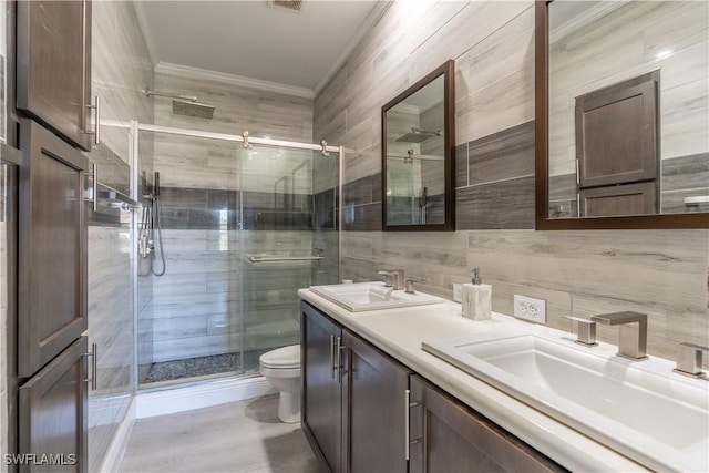 bathroom with walk in shower, crown molding, toilet, vanity, and tile walls