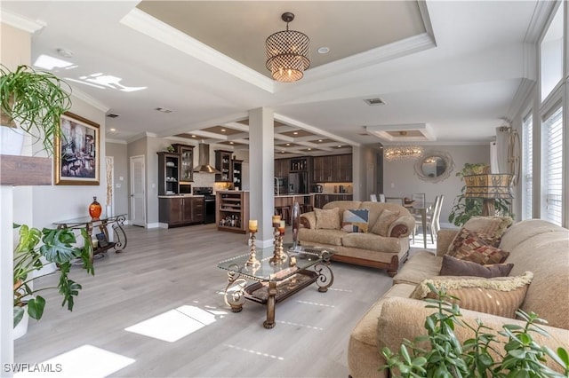 living room featuring a tray ceiling, crown molding, and light wood-type flooring