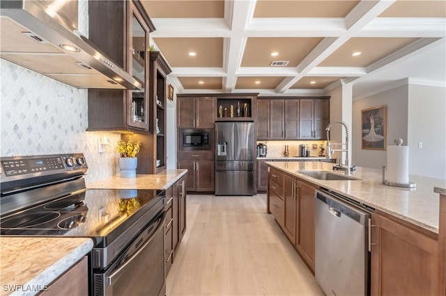 kitchen with sink, wall chimney exhaust hood, light stone counters, appliances with stainless steel finishes, and ornamental molding