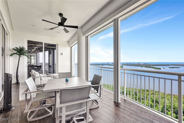 sunroom featuring ceiling fan and a water view