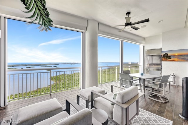 sunroom / solarium featuring a water view and ceiling fan