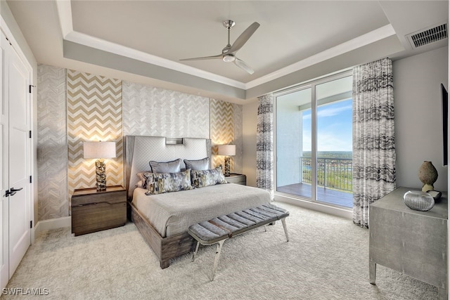 bedroom with ceiling fan, a tray ceiling, light colored carpet, access to outside, and ornamental molding