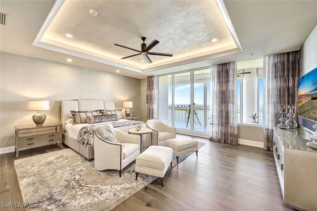 bedroom with a raised ceiling, access to exterior, ceiling fan, and dark hardwood / wood-style flooring