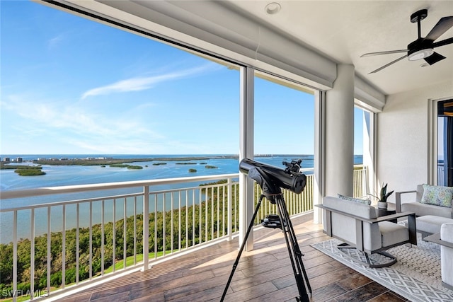 sunroom with ceiling fan and a water view