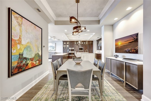 dining area with dark hardwood / wood-style flooring, a raised ceiling, crown molding, and sink