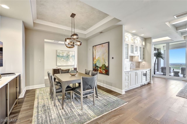 dining area featuring sink, a raised ceiling, wine cooler, dark hardwood / wood-style floors, and a notable chandelier