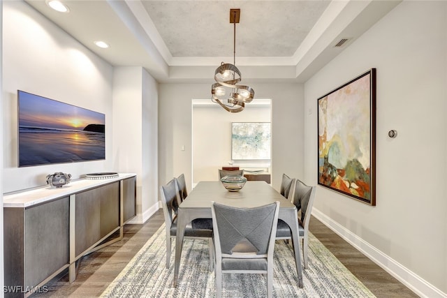 dining room featuring a raised ceiling and dark hardwood / wood-style flooring