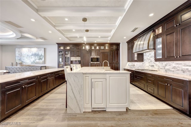 kitchen with a kitchen island with sink, sink, beam ceiling, custom range hood, and stainless steel appliances