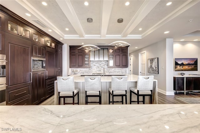 kitchen featuring built in microwave, a kitchen breakfast bar, tasteful backsplash, light stone counters, and a kitchen island