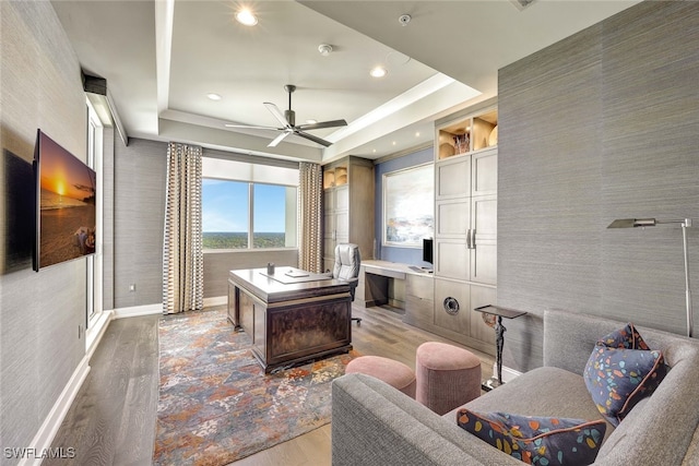 office area featuring light hardwood / wood-style flooring, a raised ceiling, and ceiling fan