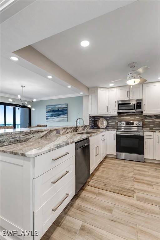 kitchen featuring light stone countertops, white cabinetry, appliances with stainless steel finishes, and decorative backsplash