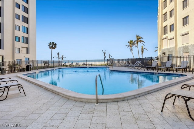 view of pool featuring a water view and a patio area