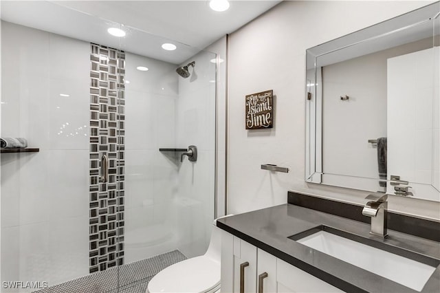 bathroom with vanity, toilet, and tiled shower