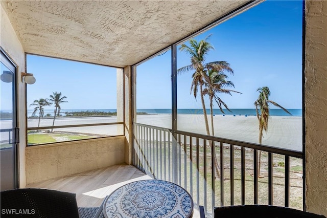 sunroom / solarium with a water view and a beach view