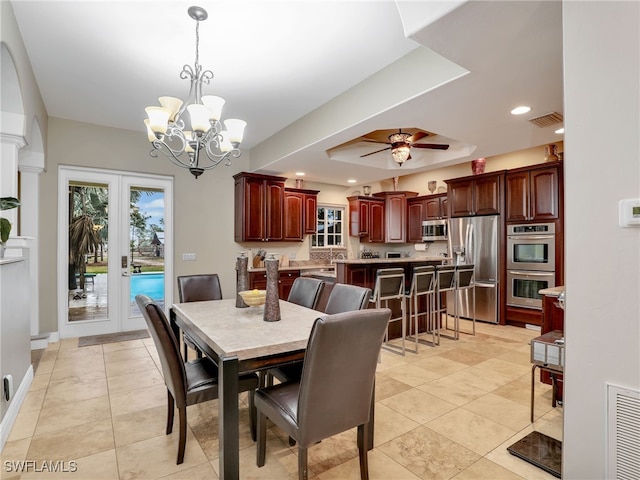 dining area featuring french doors, light tile patterned flooring, and ceiling fan with notable chandelier