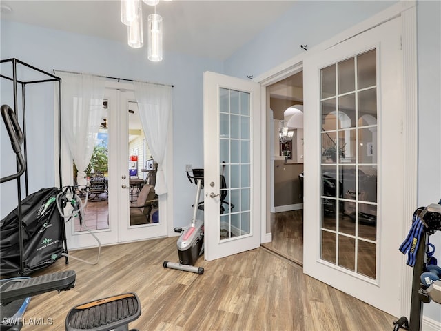 exercise room with french doors, an inviting chandelier, and hardwood / wood-style floors